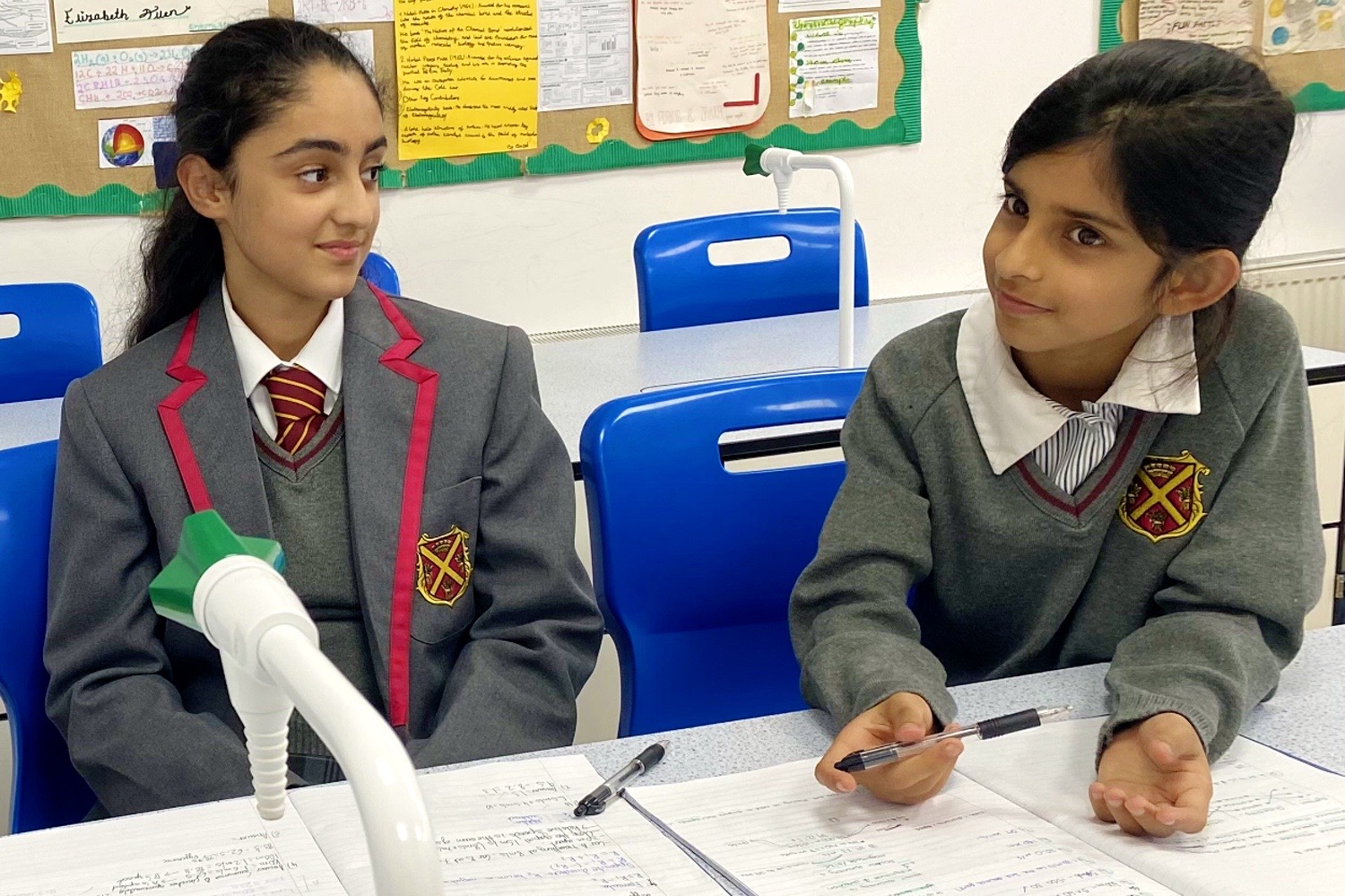 Two pupils in Queen's Square uniform at a classroom desk, working on written notes
